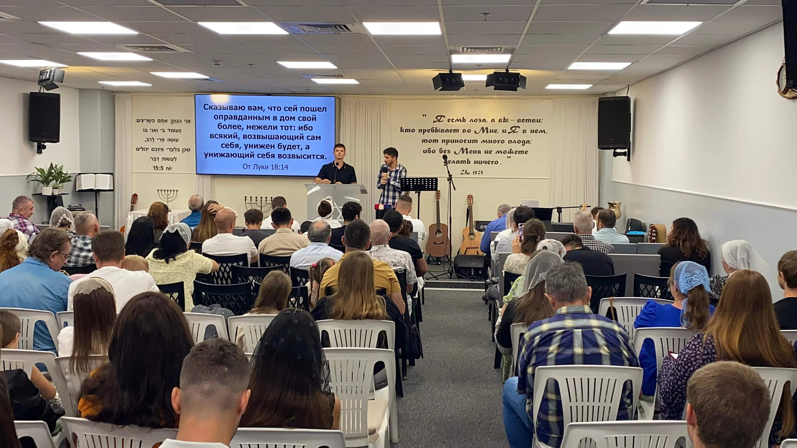 Two men on stage sharing a message with the attentive Congregation seated in the hall.