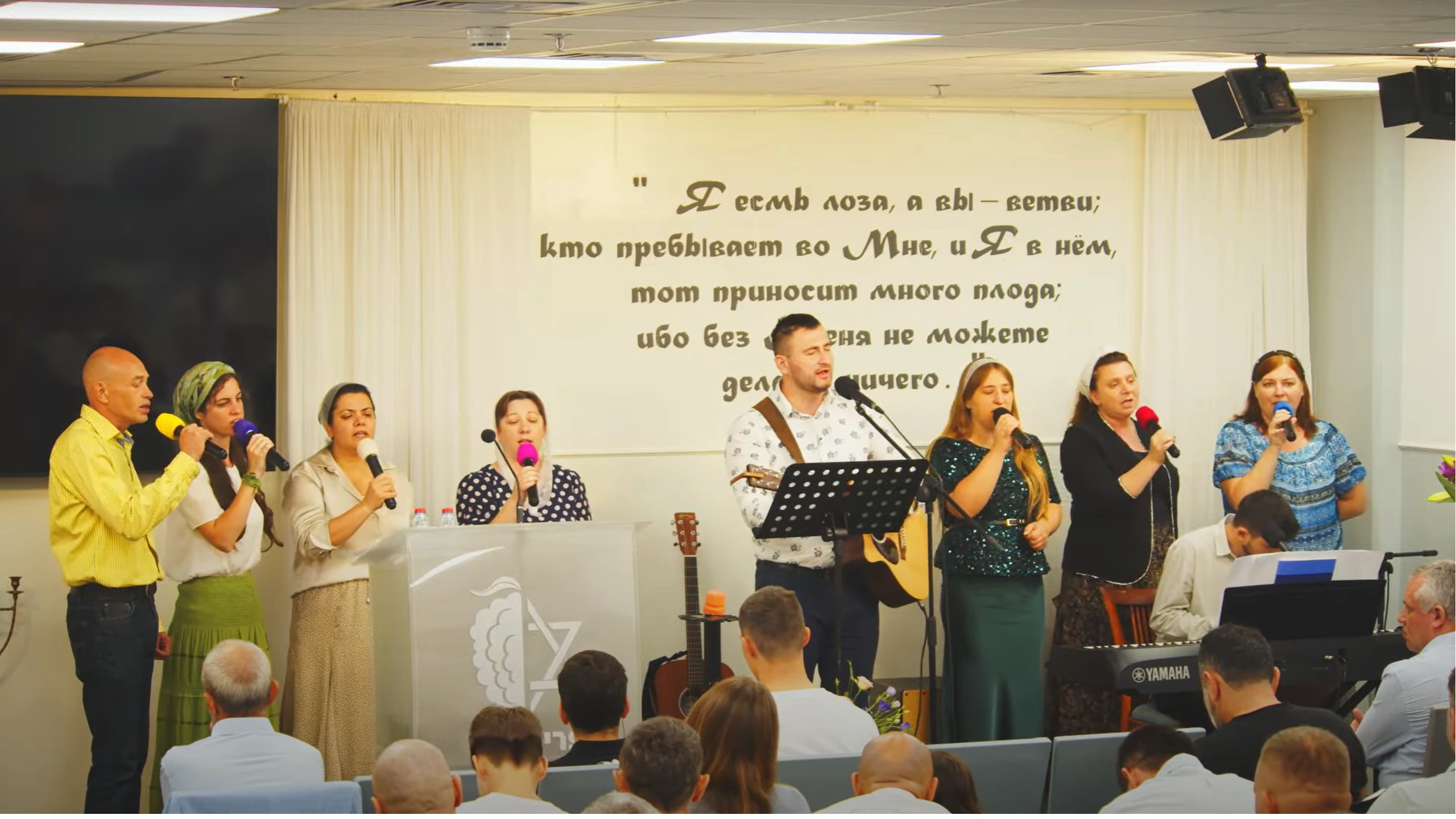 Vocalists and musicians on stage performing worship music for the seated Congregation.