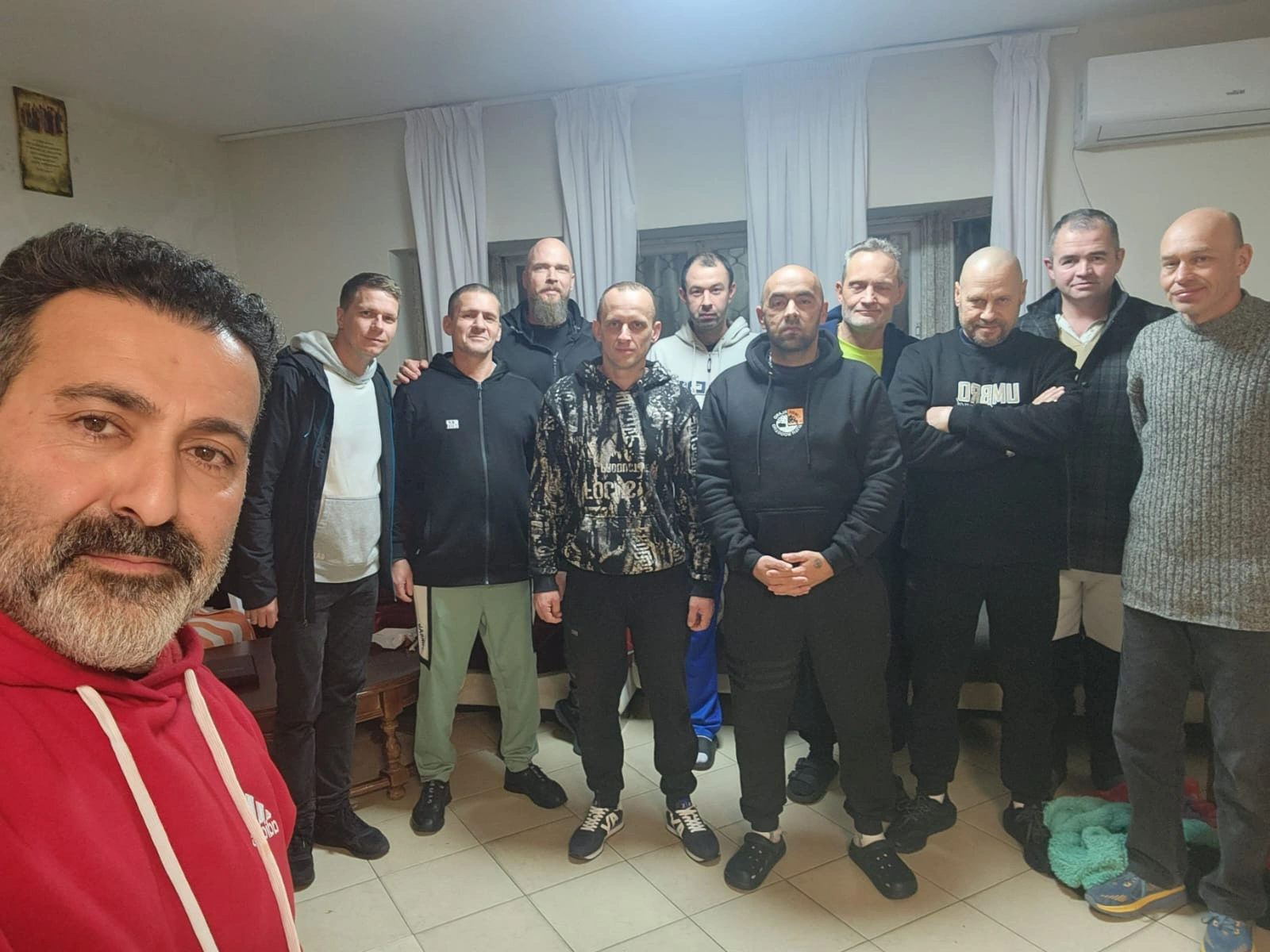 A family dressed in white standing together outdoors near a pond during a visit to the recovery home.